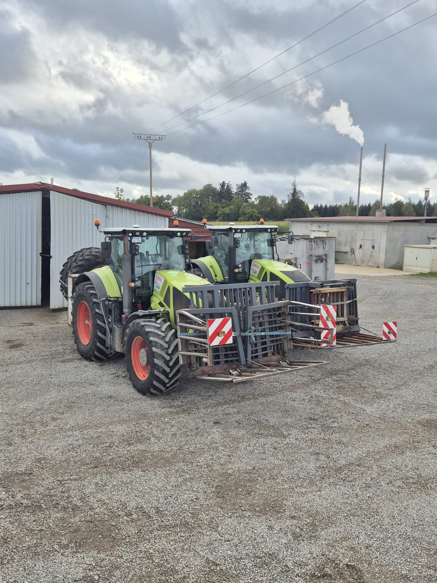 Zwei Claas Axion Schlepper mit Silageblockschneidern auf dem Hof der Biogasanlage Winterbach