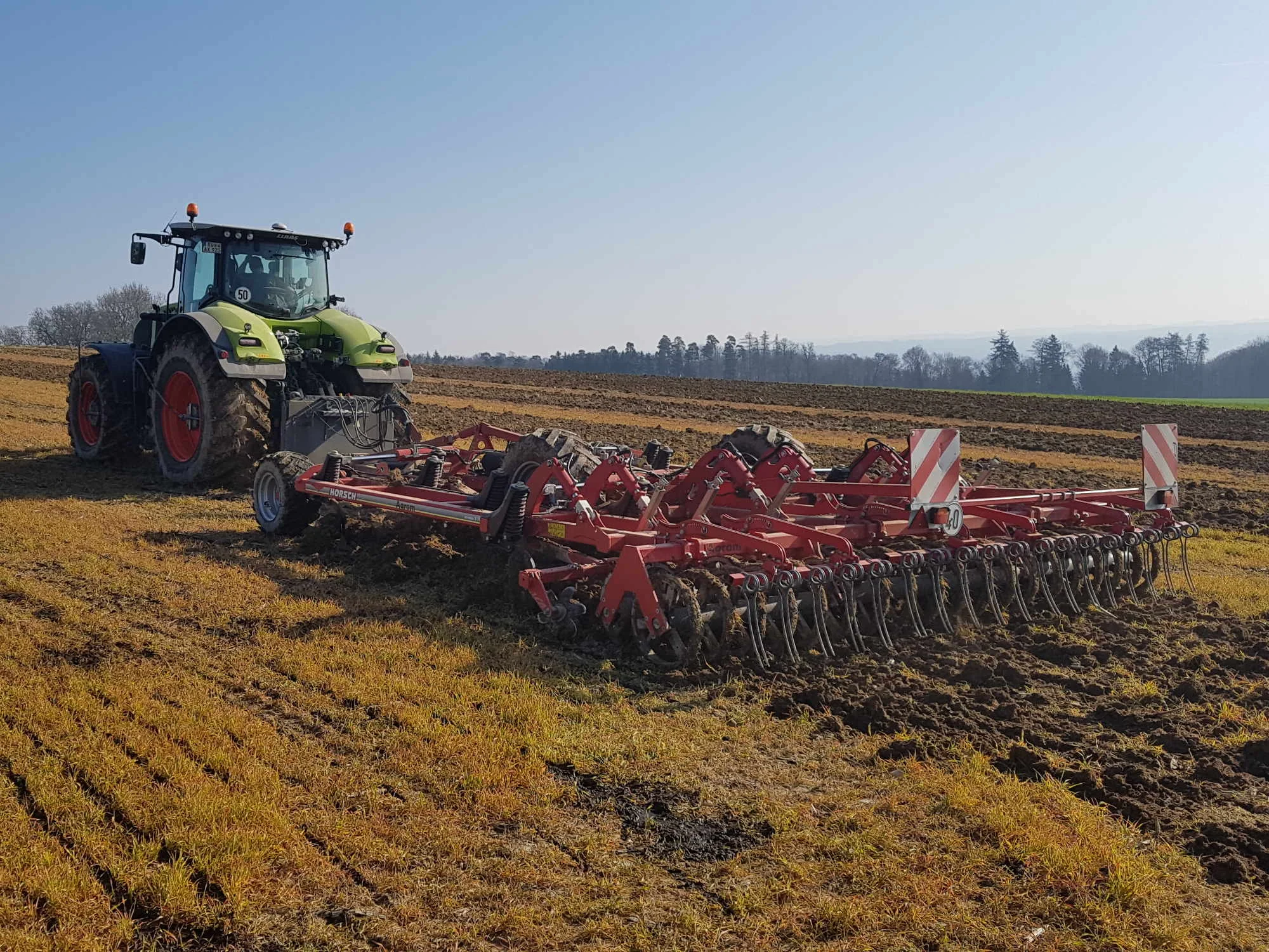 Traktor mit Bodenbearbeitungsgerät auf einem Feld bei Winterbach